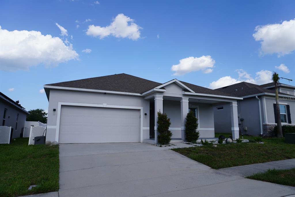 A single-story house with a two-car garage, covered porch, and light gray stucco exterior — 387 PINECREST LOOP, DAVENPORT, FL