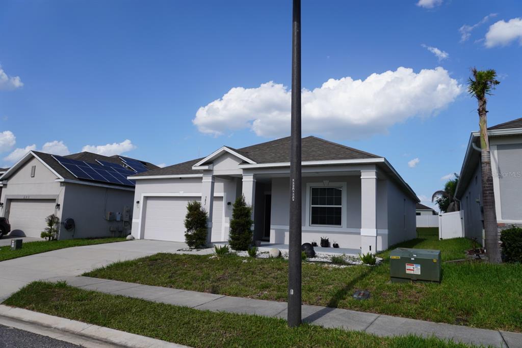 A single-story suburban house with a gray exterior, a two-car garage, and a front porch — 387 PINECREST LOOP, DAVENPORT, FL