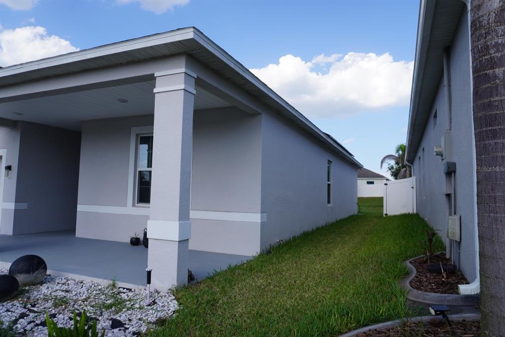 A view of a gray house exterior featuring a covered porch and a side yard — 387 PINECREST LOOP, DAVENPORT, FL