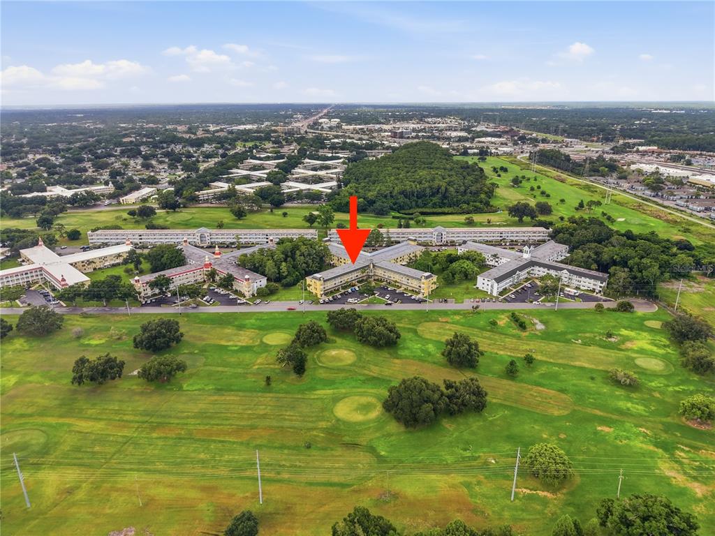 An aerial view shows a multi-story apartment building surrounded by a golf course — 2458 FLORENTINE WAY UNIT 34, CLEARWATER, FL