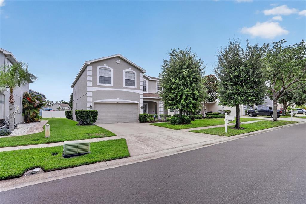A two-story suburban house with a gray exterior, a two-car garage, and a manicured lawn — 8821 N RIVER ROAD, TAMPA, FL