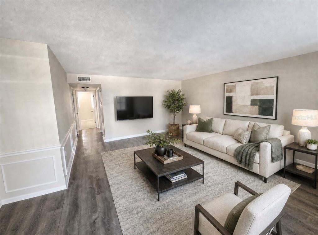 A living room features a beige sofa, a dark coffee table, and wood-look flooring — 350 79TH AVENUE N UNIT 134, ST PETERSBURG, FL