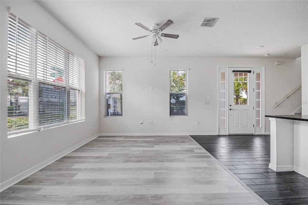 An empty living room features light wood-look flooring, a ceiling fan, and a front door — 9586 POPLAR RIDGE AVENUE, ORLANDO, FL
