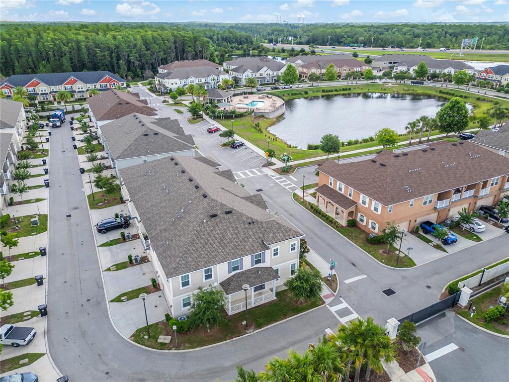 An aerial view shows multi-story residential buildings, a community pool, and a pond — 9586 POPLAR RIDGE AVENUE, ORLANDO, FL