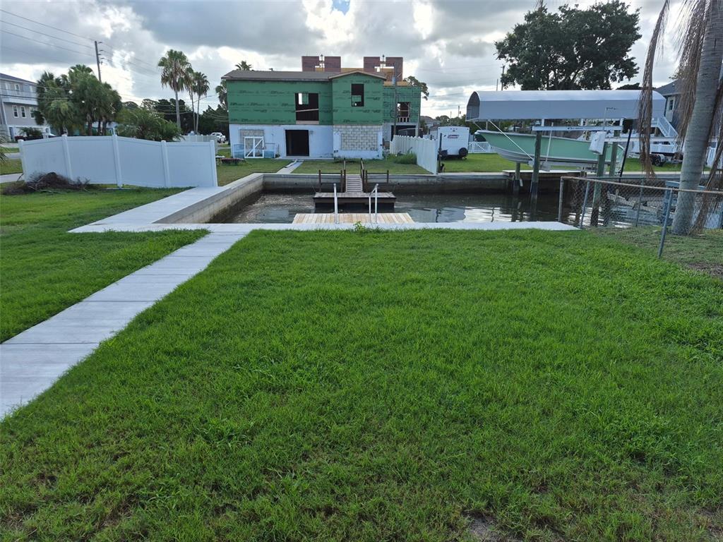 A grassy backyard features a concrete walkway leading to a boat slip and wooden dock — 13934 SOMMERS AVENUE, HUDSON, FL