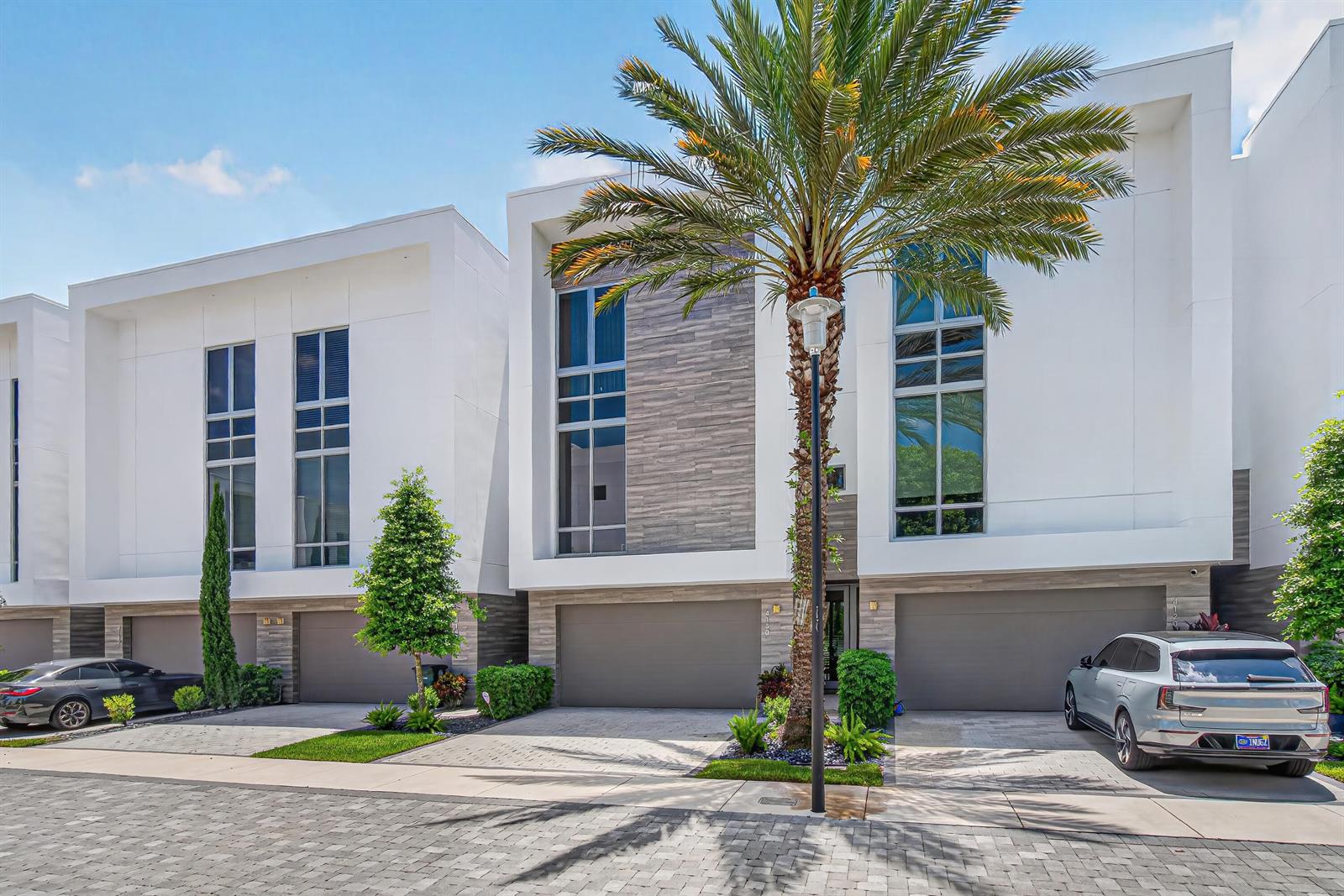 A row of modern townhouses features white facades, gray stone accents, and paved driveways — 4130 NW 17th Avenue, Boca Raton FL 33431, BOCA RATON, FL