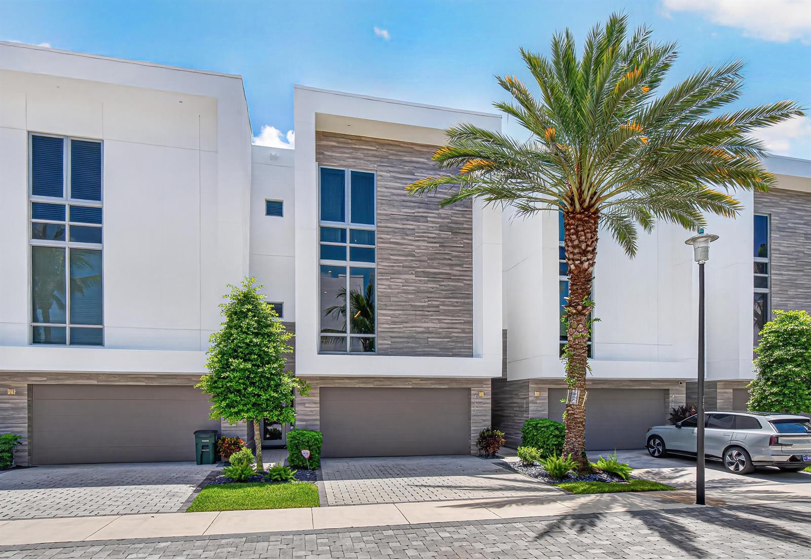 A row of modern townhomes features white facades, gray stone accents, and attached garages — 4130 NW 17th Avenue, Boca Raton FL 33431, BOCA RATON, FL