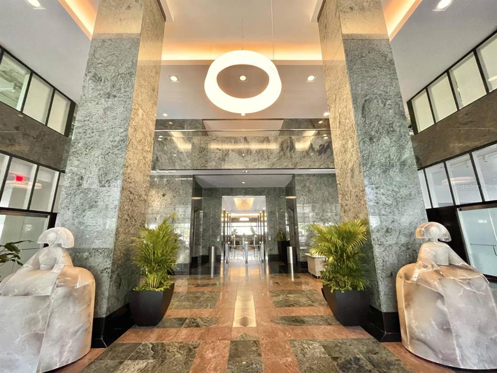 A grand lobby features marble walls, tiled floors, two large sculptures, and a circular light fixture — 250 MUÑOZ RIVERA, SAN JUAN, PR