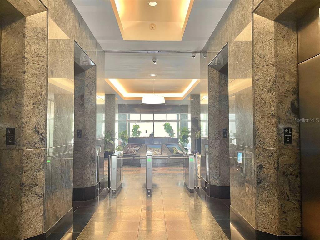 A modern building lobby features marble walls, elevator banks, and a security turnstile entrance — 250 MUÑOZ RIVERA, SAN JUAN, PR