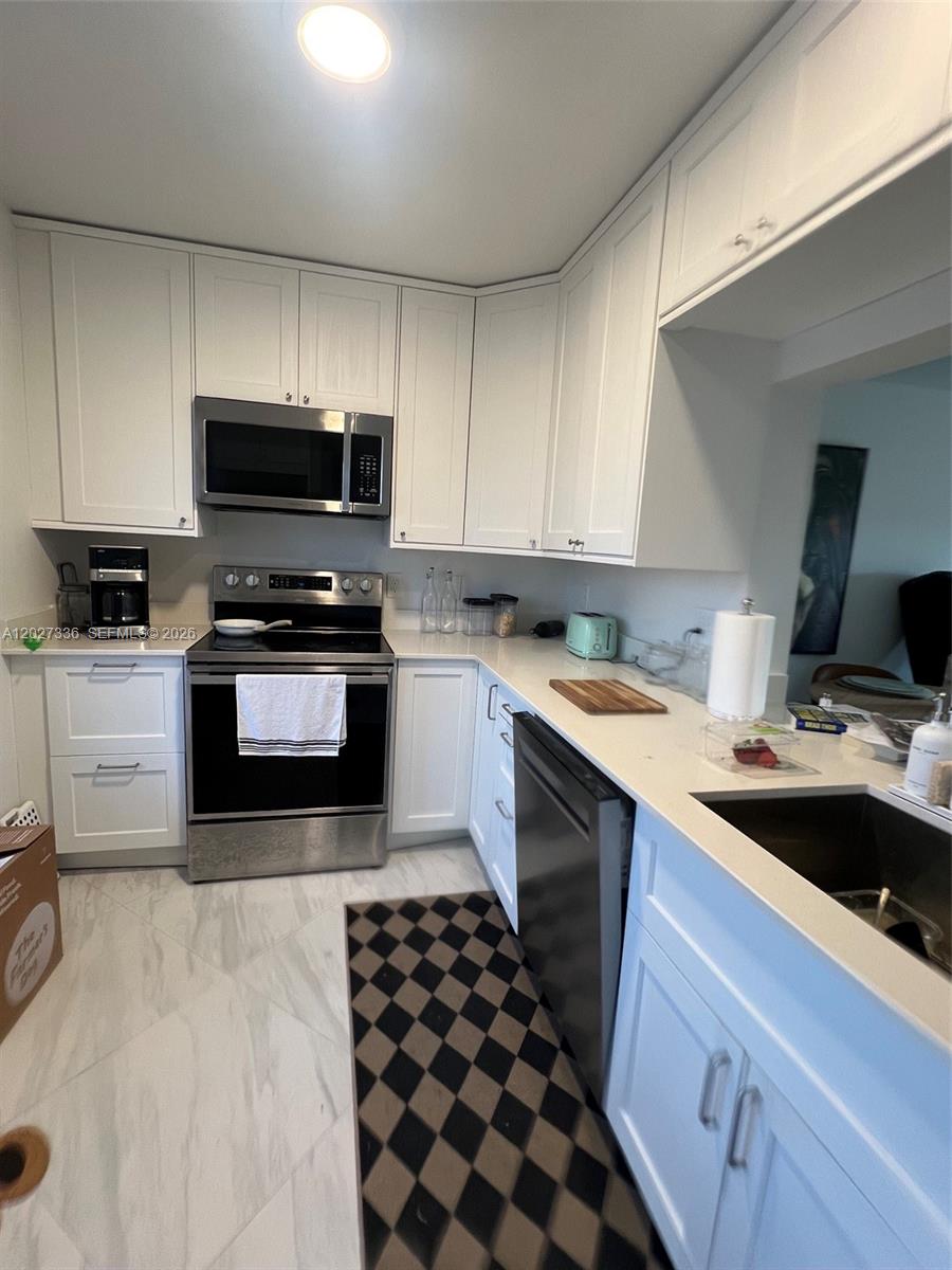 A kitchen features white cabinets, stainless steel appliances, and white countertops — 1000 NE 14th Ave # 408, Hallandale Beach FL 33009, HALLANDALE BEACH, FL