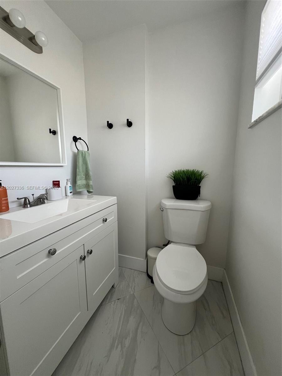 A small bathroom features a white vanity, a toilet, and light-colored tile flooring — 1000 NE 14th Ave # 408, Hallandale Beach FL 33009, HALLANDALE BEACH, FL