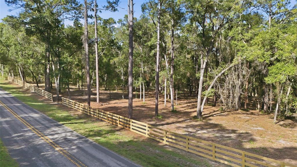 An aerial view shows a fenced, wooded lot bordering a paved road — 5230 S ROBERT BLAKE AVENUE, INVERNESS, FL
