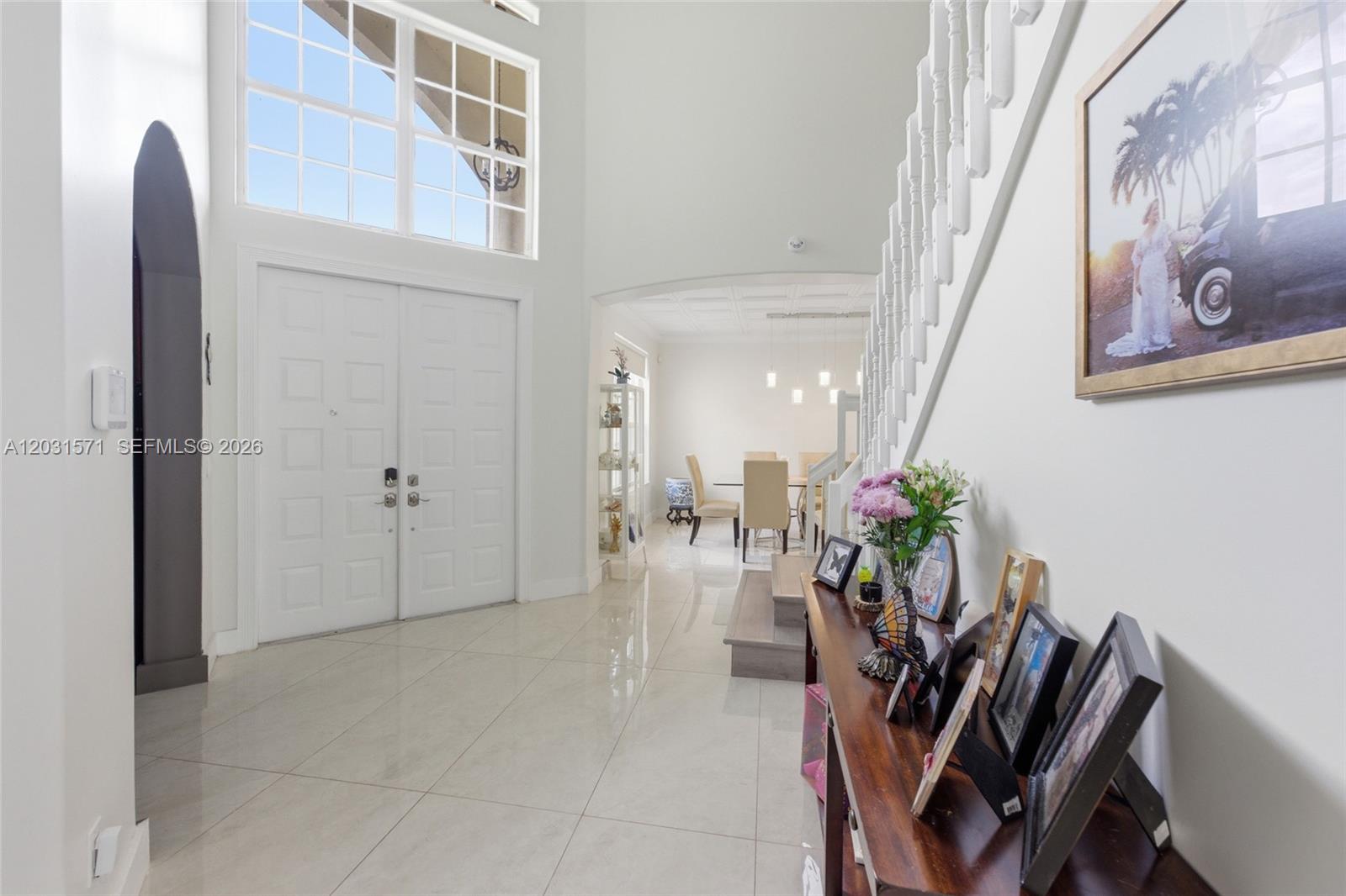 A bright foyer features white tile floors, a grand staircase, and a view into the dining room — 3511 SW 145th Ave, Miramar FL 33027, MIRAMAR, FL