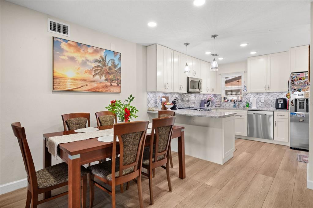 A dining area with a wooden table and chairs sits next to a modern kitchen — 5400 34TH STREET W UNIT I3, BRADENTON, FL