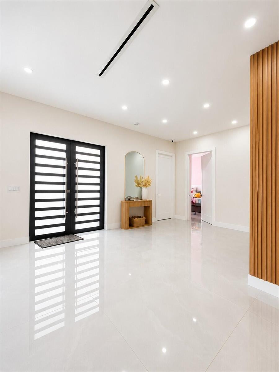 A bright entryway features white tile floors, a black double door, and wood slat wall accents — 345 N Jinete Street, Clewiston FL 33440, CLEWISTON, FL
