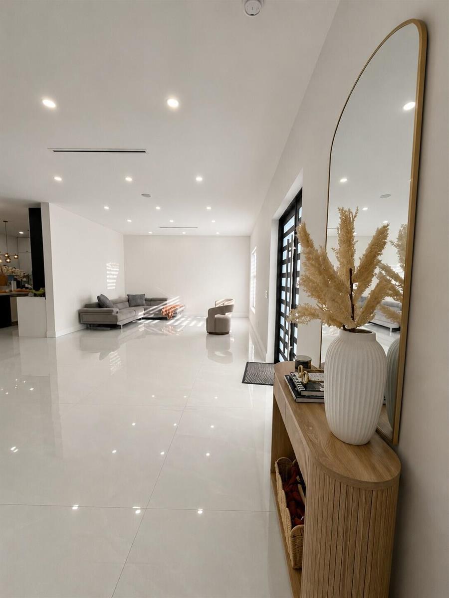 A modern living room with white tile floors, a grey sectional sofa, and an entryway console — 345 N Jinete Street, Clewiston FL 33440, CLEWISTON, FL