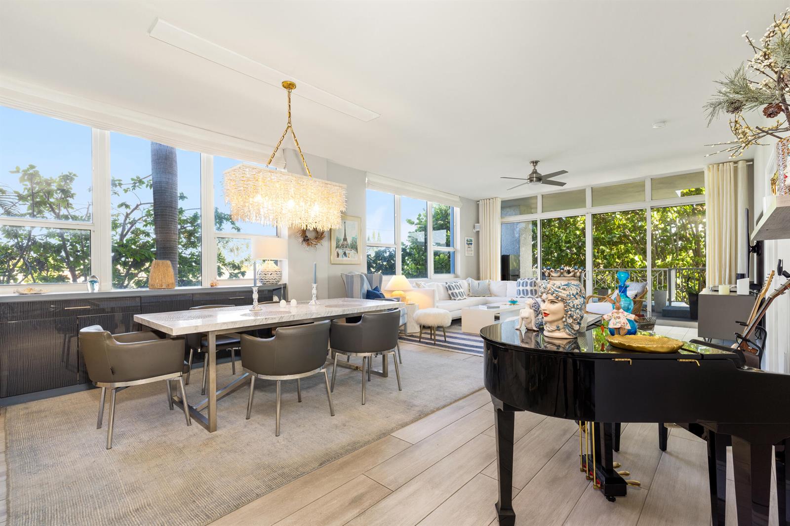 A bright living and dining area features a grand piano, marble table, and large windows — 701 SE 21st Avenue # 201, Deerfield Beach FL 33441, DEERFIELD BEACH, FL