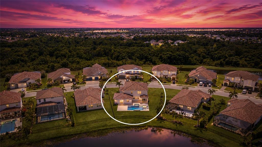 An aerial view shows a two-story house with a backyard pool at sunset — 3530 BIG SKY WAY, BRADENTON, FL