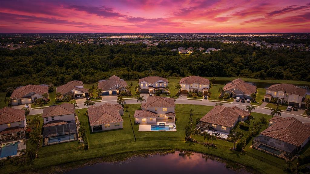 An aerial view shows a suburban neighborhood of houses with pools at sunset — 3530 BIG SKY WAY, BRADENTON, FL