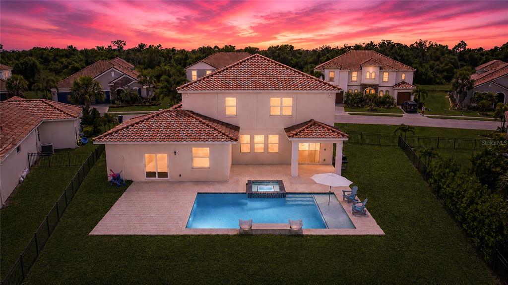 An aerial view of a two-story house with a backyard pool and a sunset sky — 3530 BIG SKY WAY, BRADENTON, FL