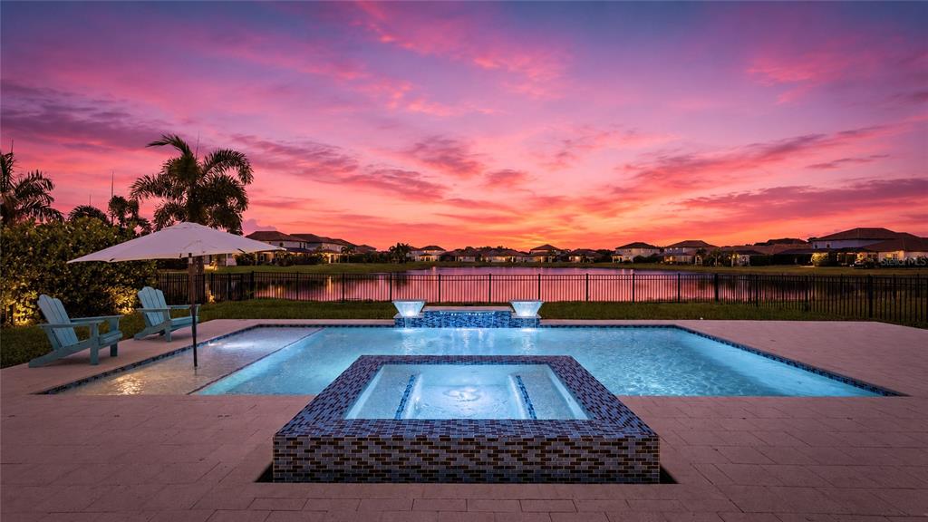 A backyard swimming pool and hot tub overlook a lake at sunset — 3530 BIG SKY WAY, BRADENTON, FL