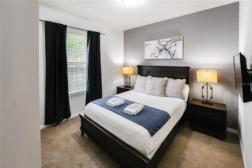 A bedroom features a dark wood bed frame, two nightstands with lamps, and black curtains — 1885 GOBI DRIVE, KISSIMMEE, FL