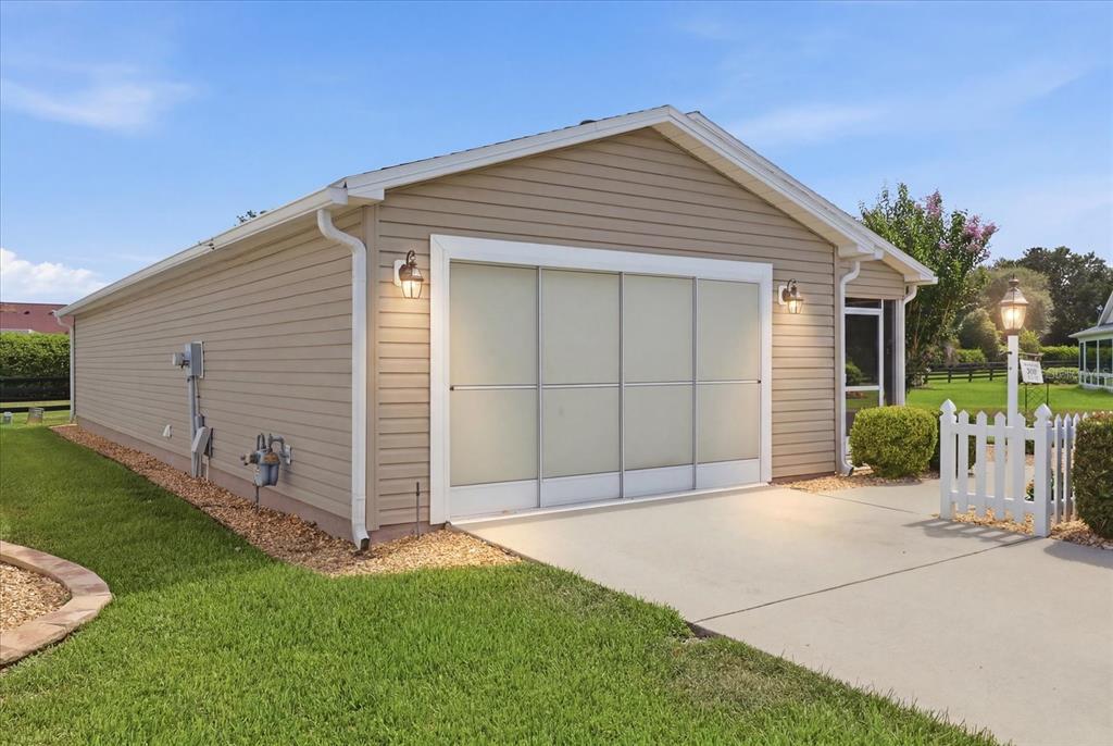 A beige house exterior features a sliding screen door over the garage opening — 2348 RILEY ROAD, THE VILLAGES, FL
