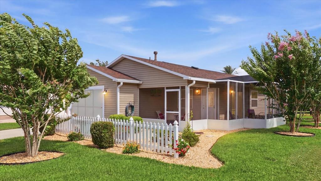 A tan single-story house with a white picket fence, screened porch, and landscaped front yard — 2348 RILEY ROAD, THE VILLAGES, FL