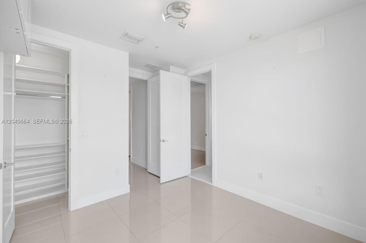 An empty room features white walls, light tile flooring, a closet, and two doorways — 10471 NW 66th St, Doral FL 33178, DORAL, FL