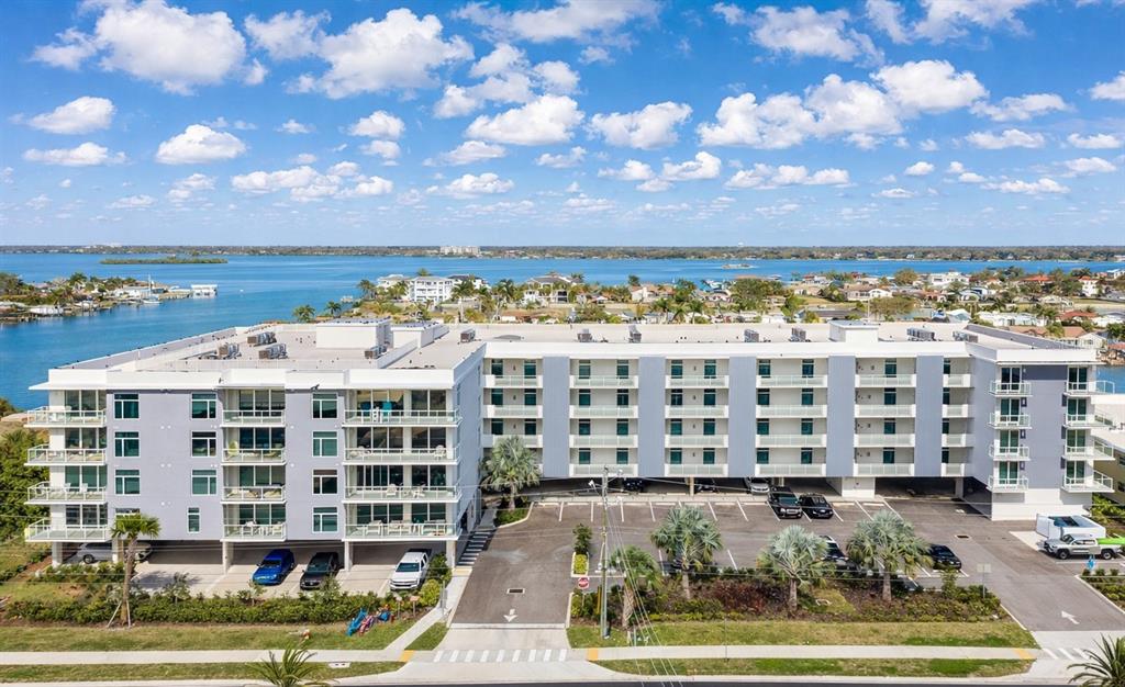 An aerial view of a multi-story apartment building with a parking lot and waterfront — 415 ISLAND WAY UNIT 402, CLEARWATER BEACH, FL