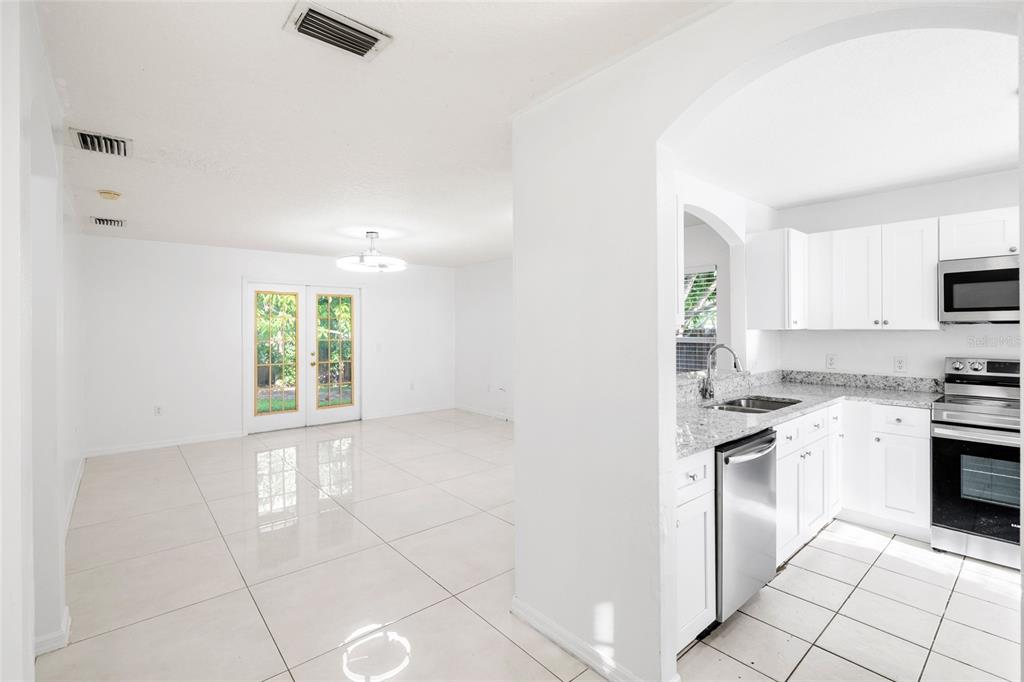 A bright kitchen with white cabinets and granite countertops opens into a tiled dining area — 10001 FLORENCE AVENUE N, TAMPA, FL