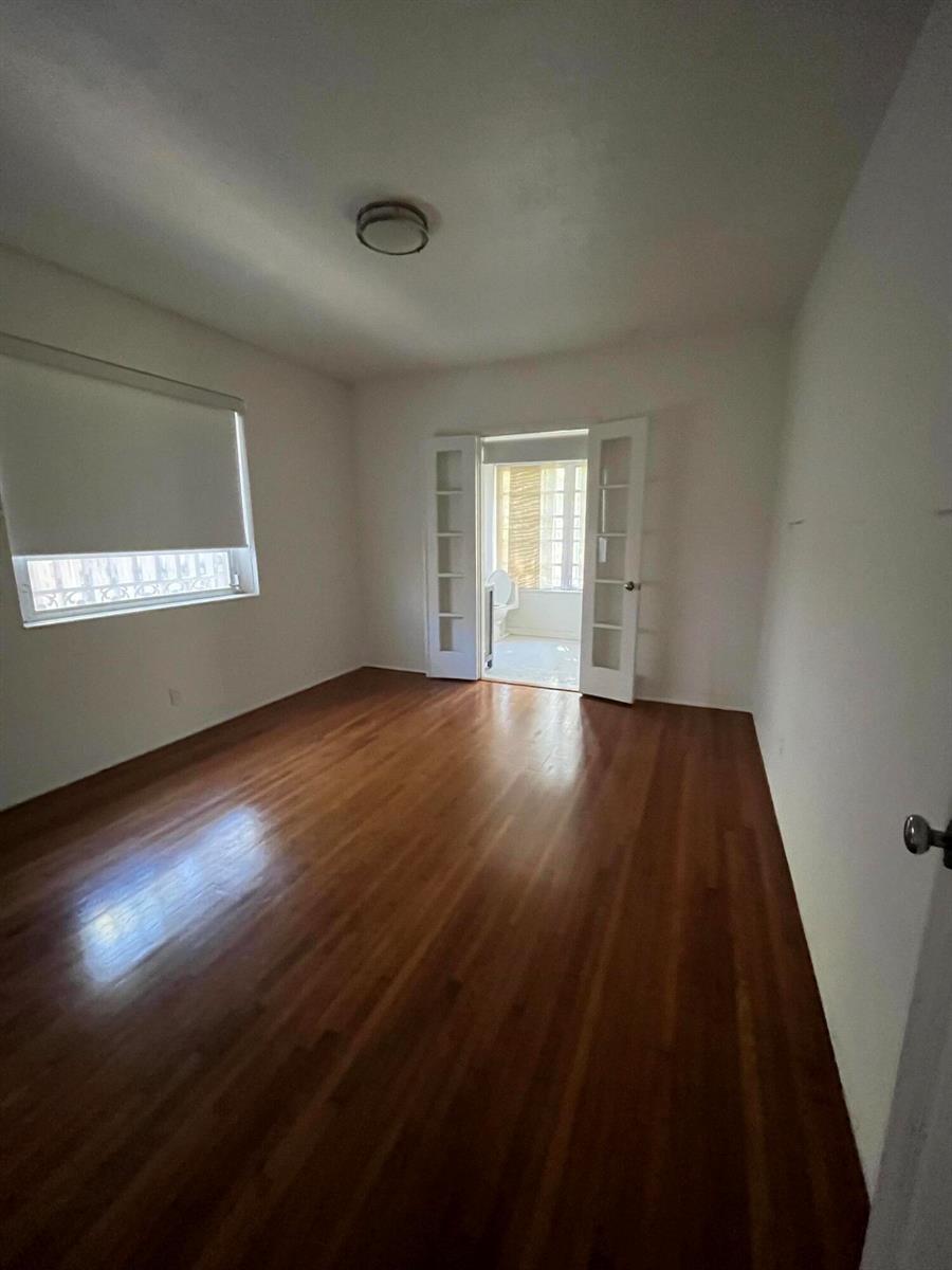 An empty room with hardwood floors, a window with a shade, and French doors — 175 SW 25th Road, Miami FL 33129, MIAMI, FL