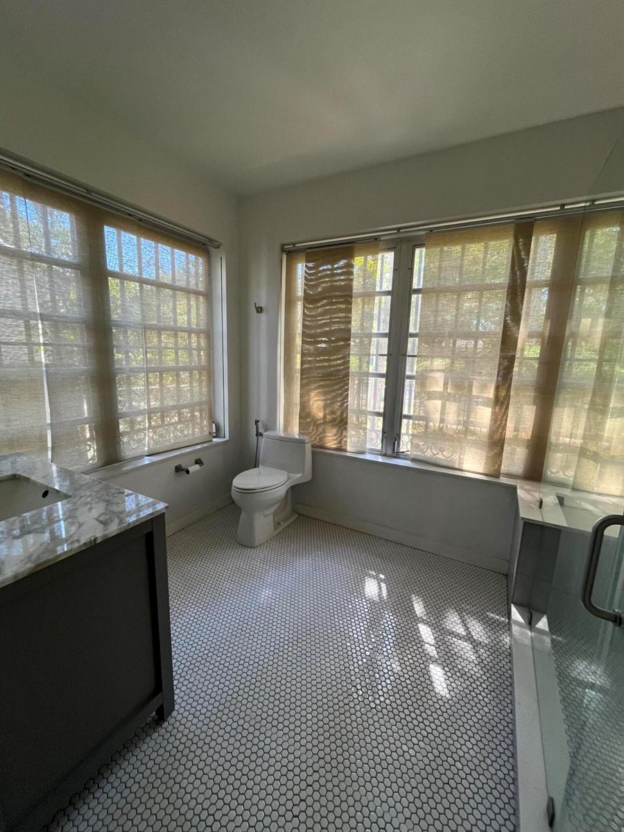 A bathroom features a marble-topped vanity, a toilet, and white penny tile flooring — 175 SW 25th Road, Miami FL 33129, MIAMI, FL