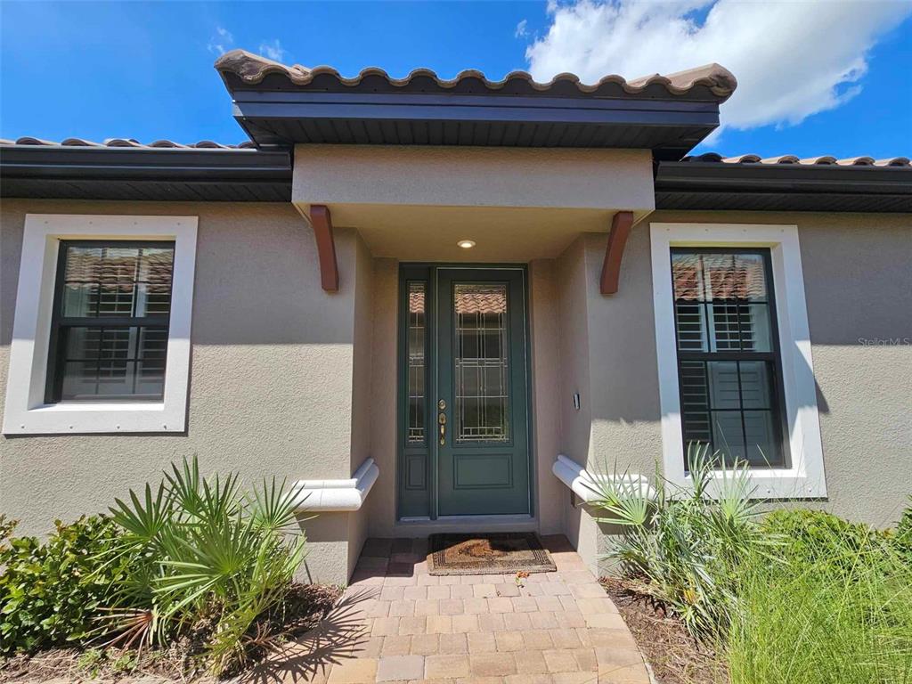 The exterior of a house features a green front door with glass panels and windows — 3270 FRANCOA DRIVE, ODESSA, FL