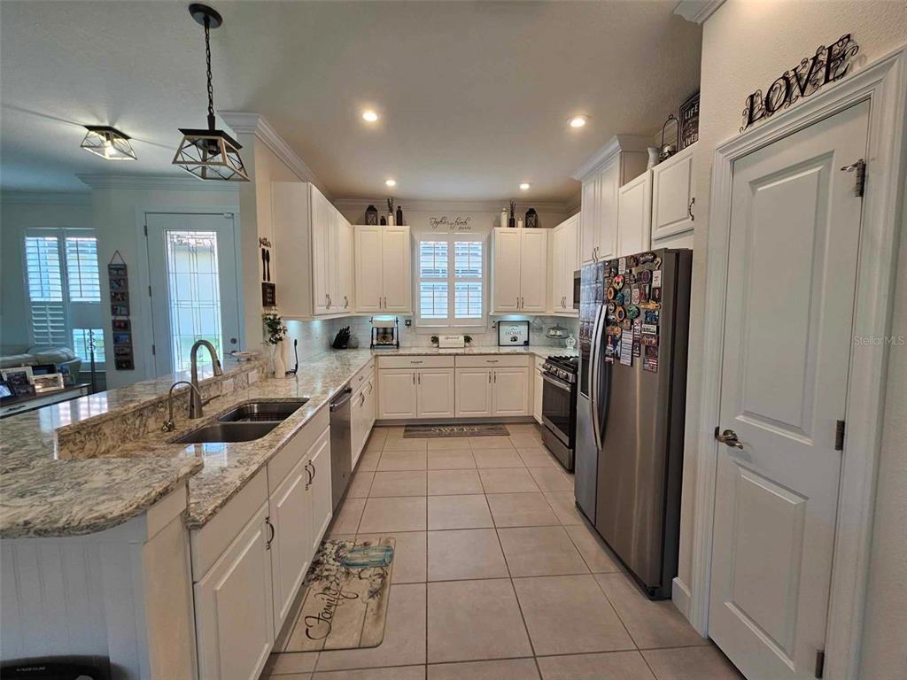 A kitchen features white cabinets, granite countertops, stainless steel appliances, and tile flooring — 3270 FRANCOA DRIVE, ODESSA, FL