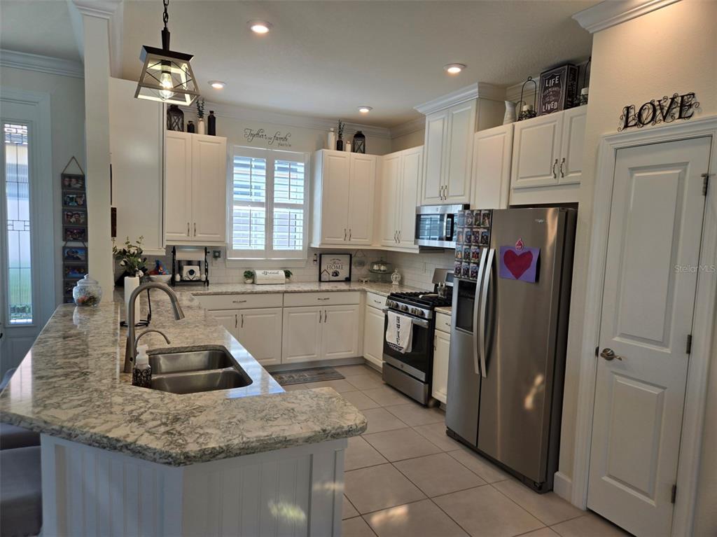 A kitchen with white cabinets, granite countertops, stainless steel appliances, and a large island — 3270 FRANCOA DRIVE, ODESSA, FL