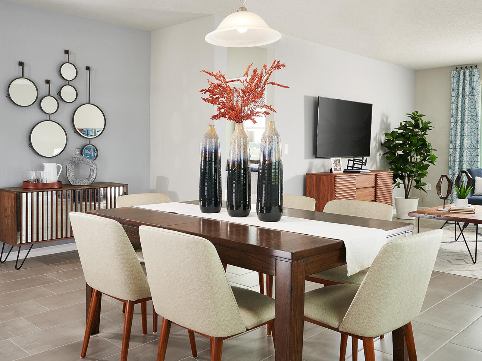 A dining room features a dark wood table, upholstered chairs, and a decorative wall mirror arrangement — 5489 Hampton Park Circle, Vero Beach FL 32966, VERO BEACH, FL