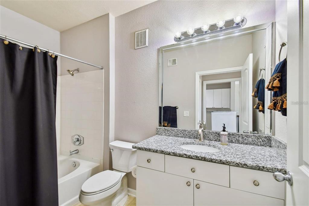 A bathroom features a granite vanity, white cabinets, a toilet, and a shower-tub combination — 4221 W SPRUCE STREET UNIT 2323, TAMPA, FL