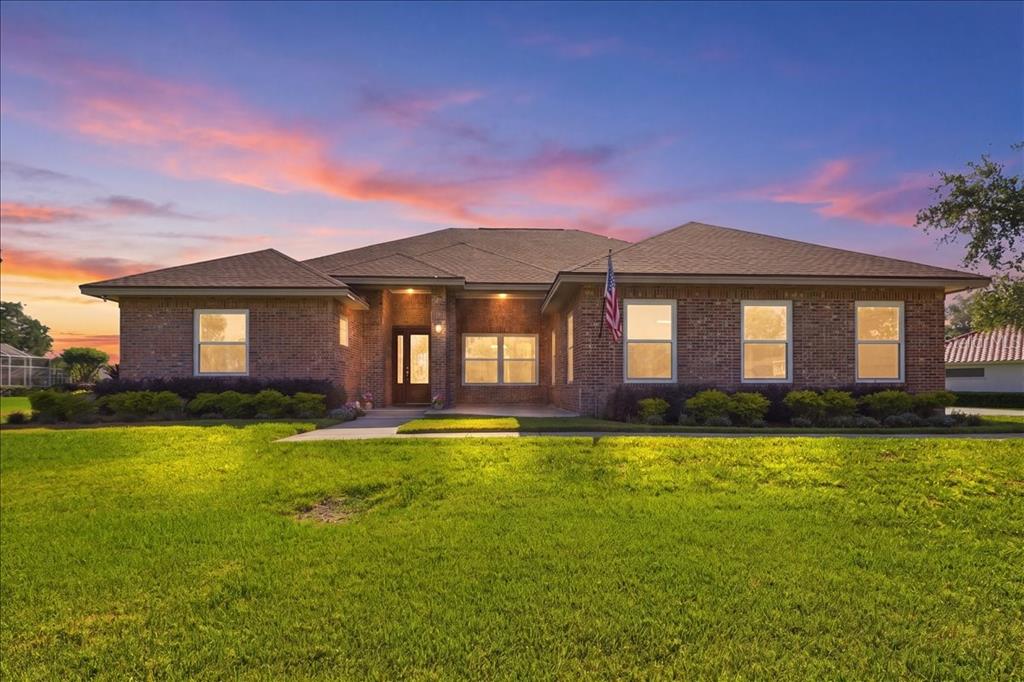 A single-story brick house with a hip roof and a front lawn at sunset — 17825 SIMMS ROAD, ODESSA, FL