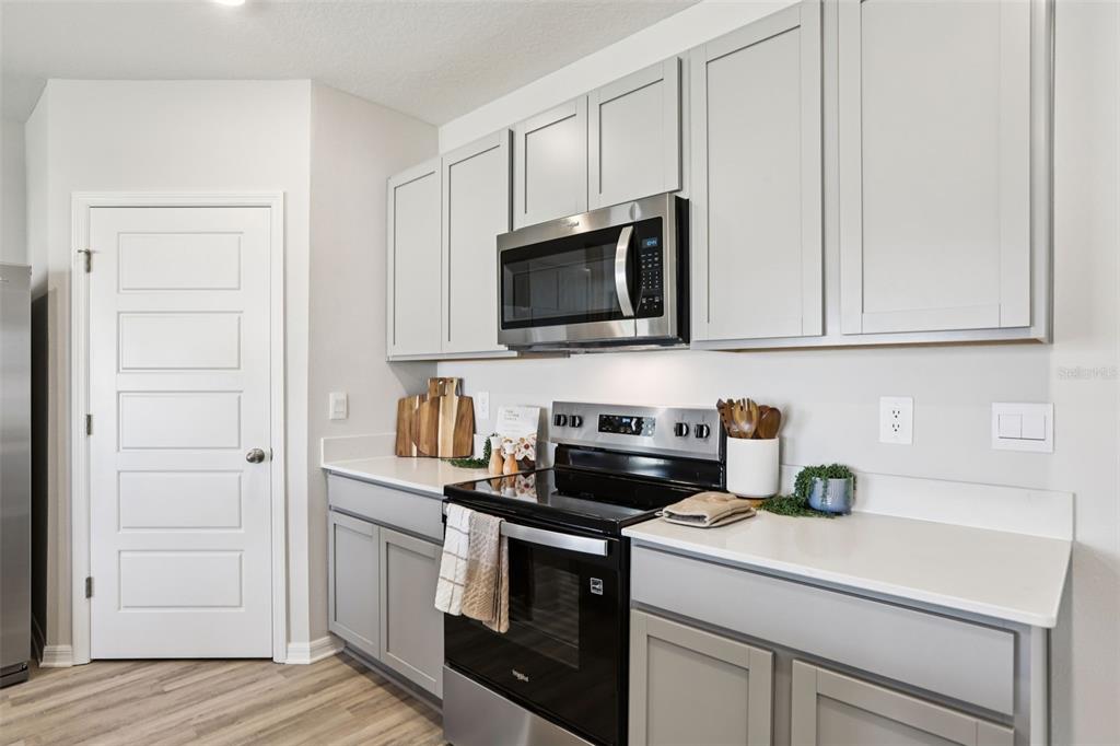 A kitchen features grey cabinets, stainless steel appliances, and white countertops — 7834 FORREST FOX WAY, LAKELAND, FL
