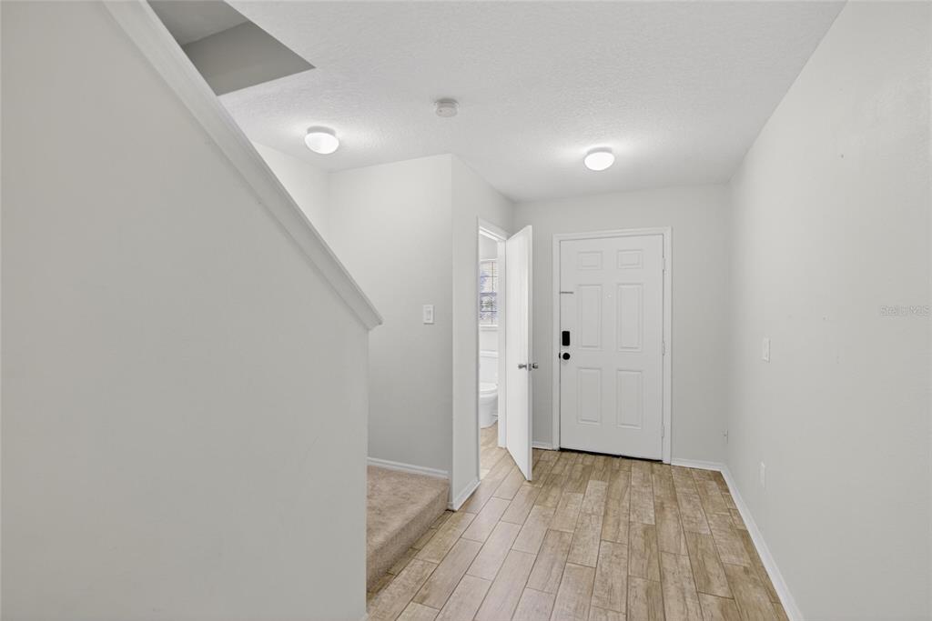 An entryway features light wood-look tile flooring, white walls, and a staircase with carpet — 2605 OLEANDER LAKES DRIVE, BRANDON, FL