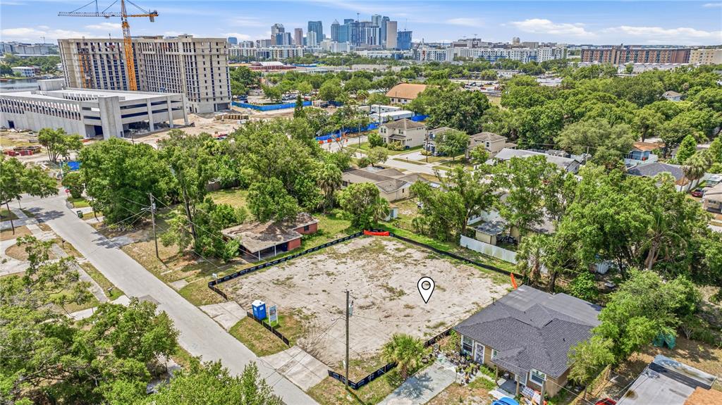 An aerial view shows a vacant, fenced-in lot situated between two houses in a city — 1712 W SAINT CONRAD STREET, TAMPA, FL