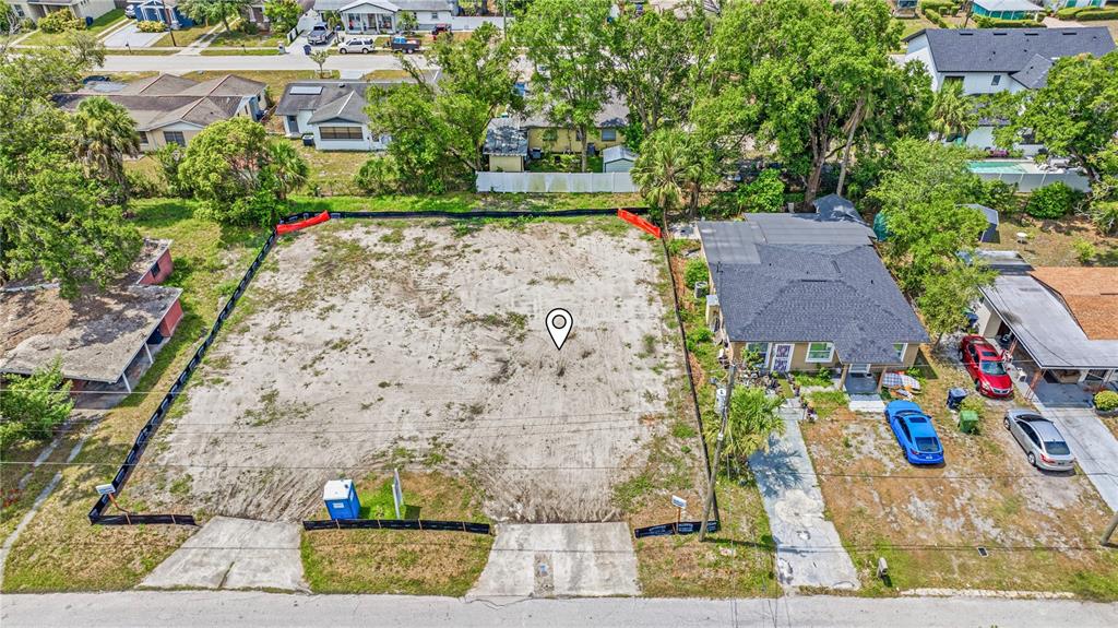An aerial view shows a vacant, fenced-in rectangular lot next to a single-story house — 1712 W SAINT CONRAD STREET, TAMPA, FL