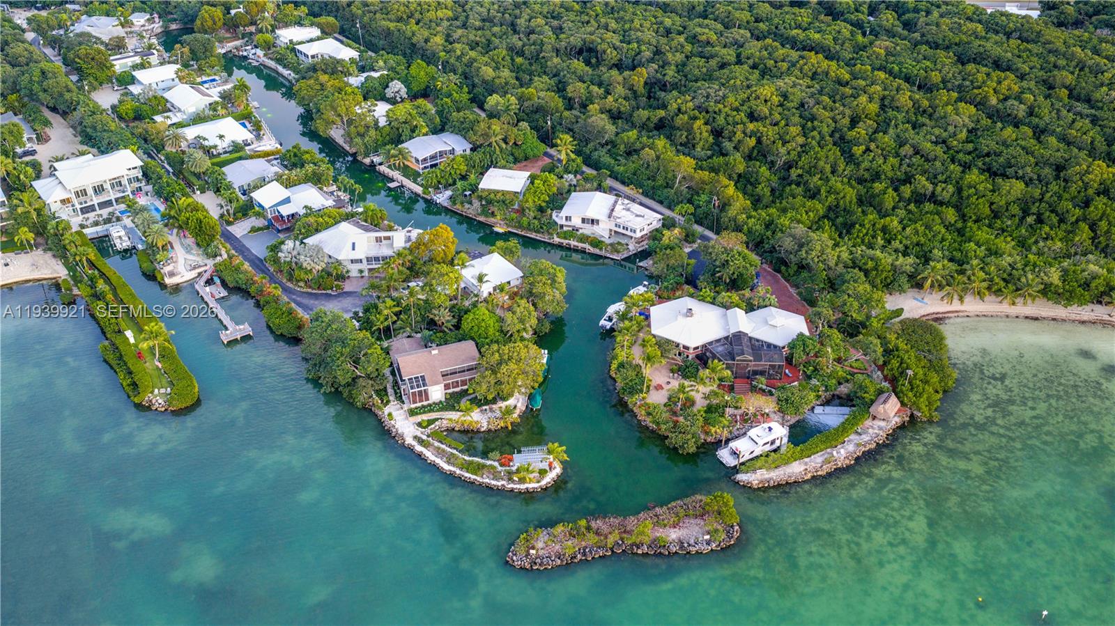 An aerial view shows waterfront houses along a canal surrounded by dense tropical vegetation — 150 Rushton Ln, Tavernier FL 33070, TAVERNIER, FL