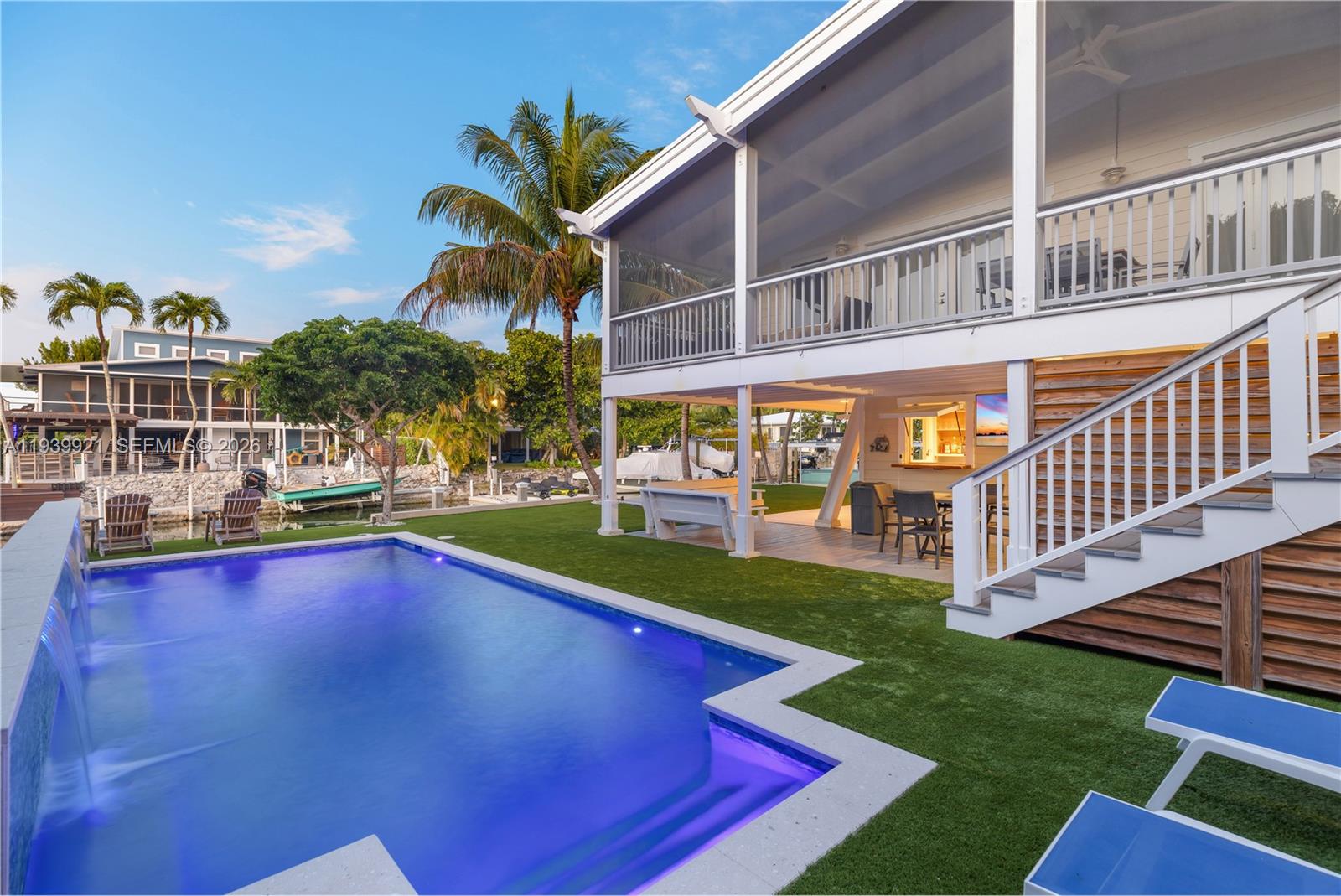 A backyard features a swimming pool, artificial turf, a covered patio, and a two-story house — 150 Rushton Ln, Tavernier FL 33070, TAVERNIER, FL