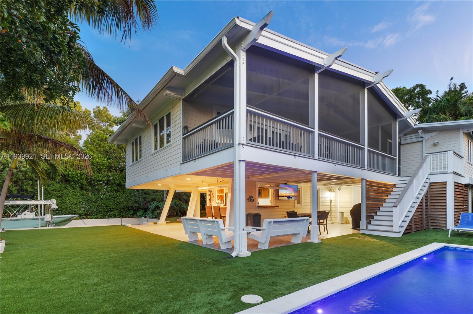 An elevated house with a screened-in porch overlooks a backyard pool and artificial turf lawn — 150 Rushton Ln, Tavernier FL 33070, TAVERNIER, FL