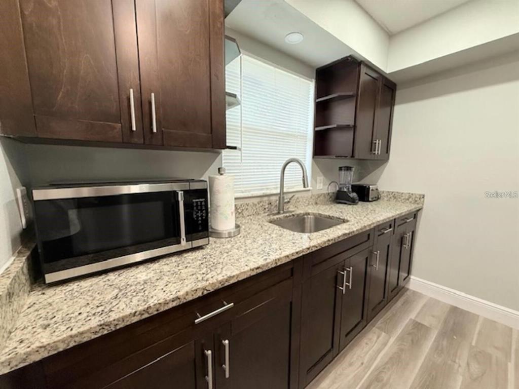 A kitchen features dark wood cabinets, granite countertops, a stainless steel sink, and a microwave — 332 AVENUE D SE, WINTER HAVEN, FL