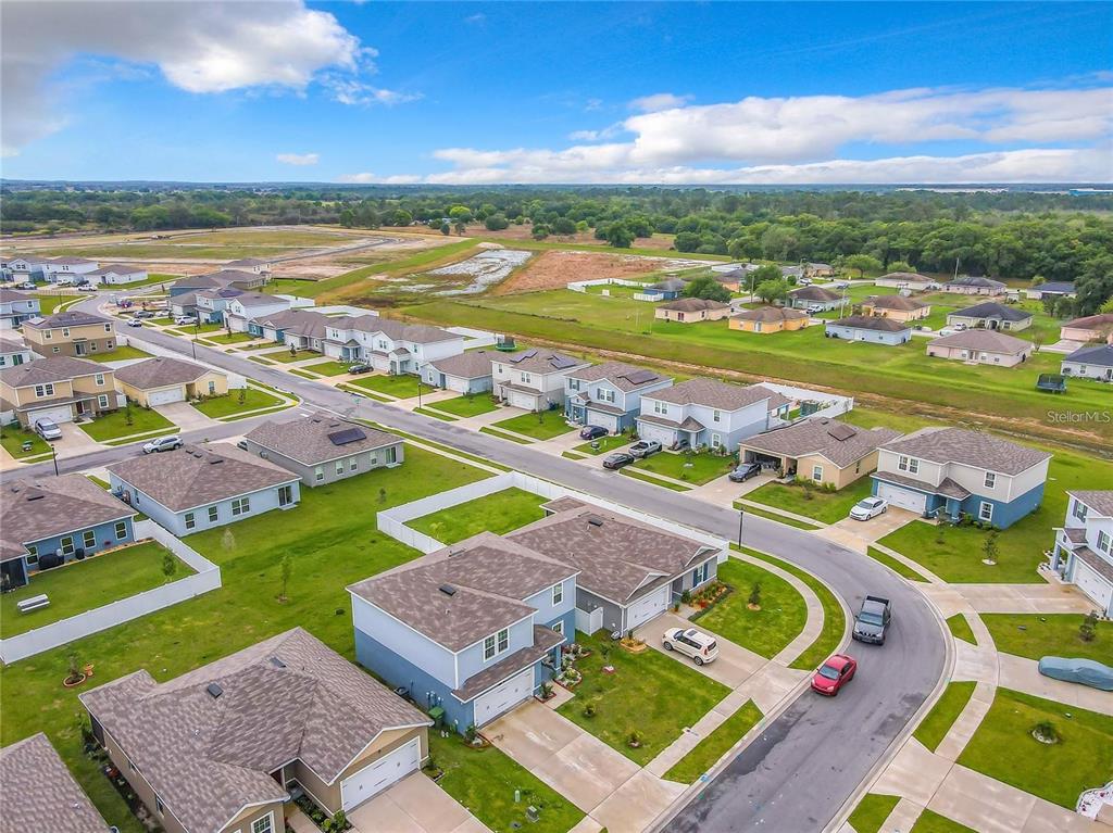 An aerial view shows a suburban neighborhood with houses, streets, and surrounding green fields — 567 EAGLE LANDING BOULEVARD, WINTER HAVEN, FL