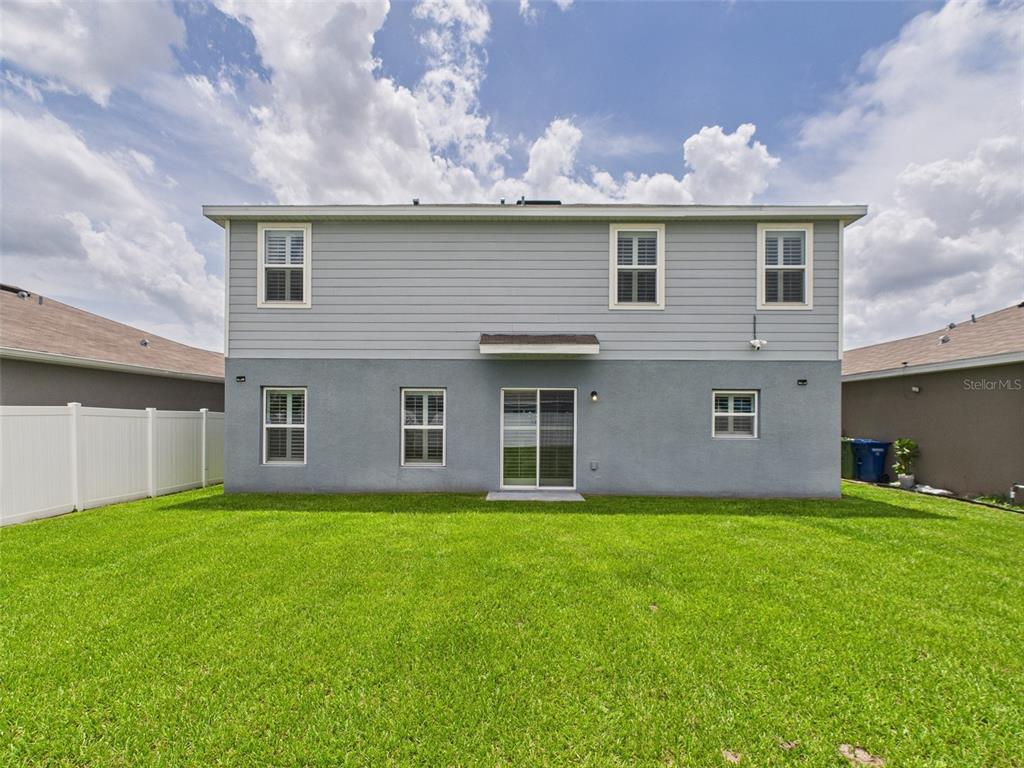 The rear exterior of a two-story house features gray siding and stucco with a lawn — 567 EAGLE LANDING BOULEVARD, WINTER HAVEN, FL
