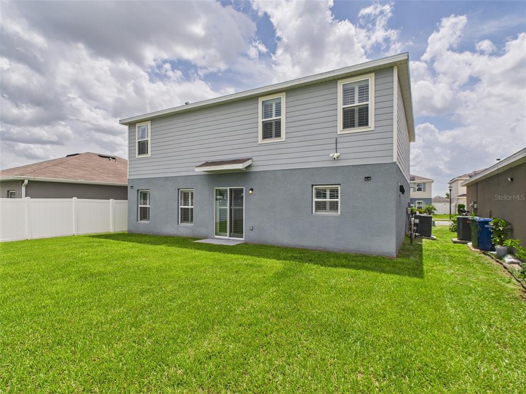 The exterior of a two-story house features gray siding and stucco with a grassy backyard — 567 EAGLE LANDING BOULEVARD, WINTER HAVEN, FL